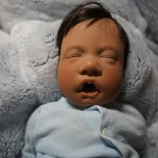 a baby doll that is laying down on a blanket related to The Ultimate Guide to Reborn Baby Beds: A Must-Have for Realistic Baby Doll Care