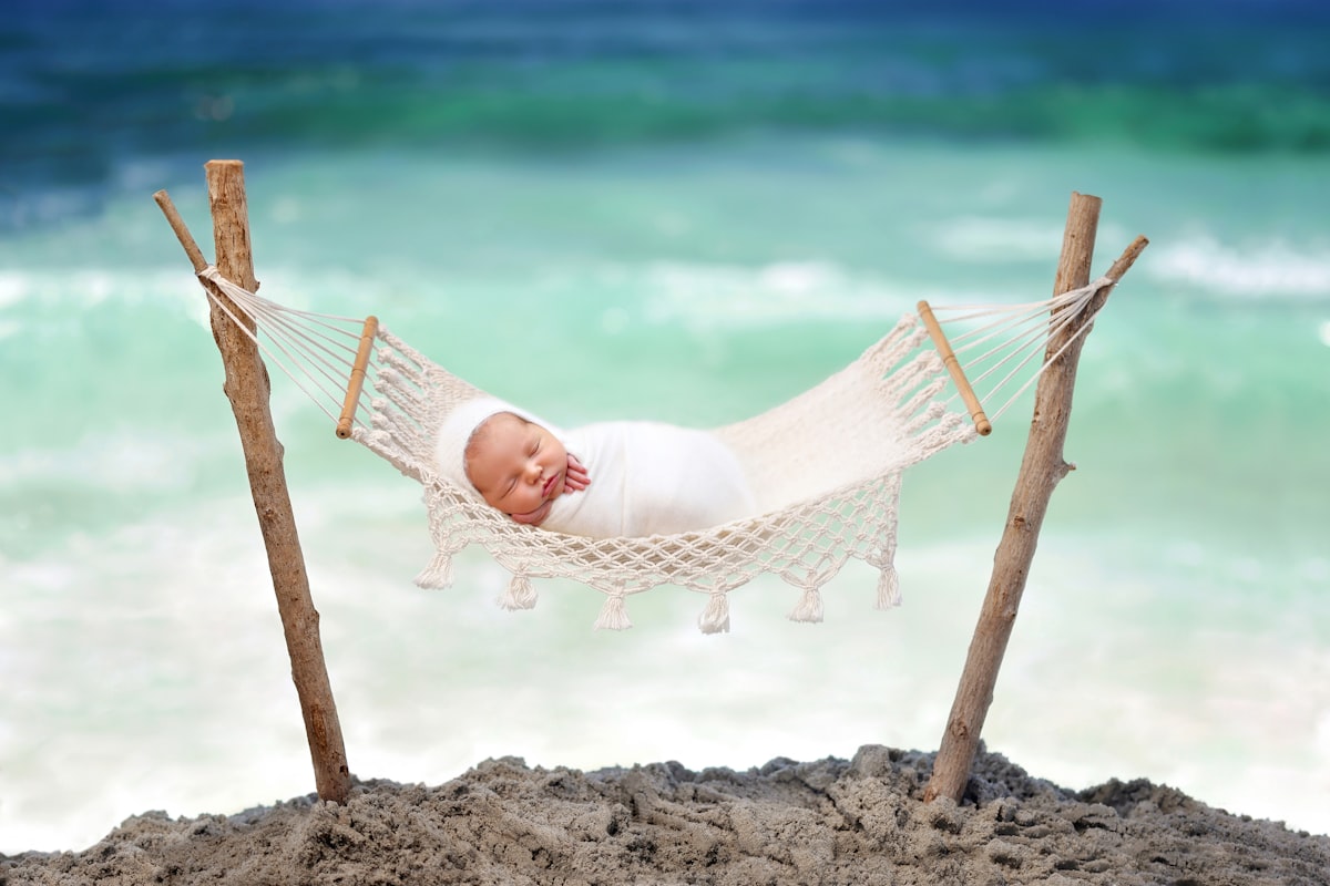 a baby laying in a hammock on the beach related to The Ultimate Guide to Choosing the Perfect Beach Crib Bedding