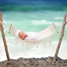 a baby laying in a hammock on the beach related to The Ultimate Guide to Choosing the Perfect Beach Crib Bedding