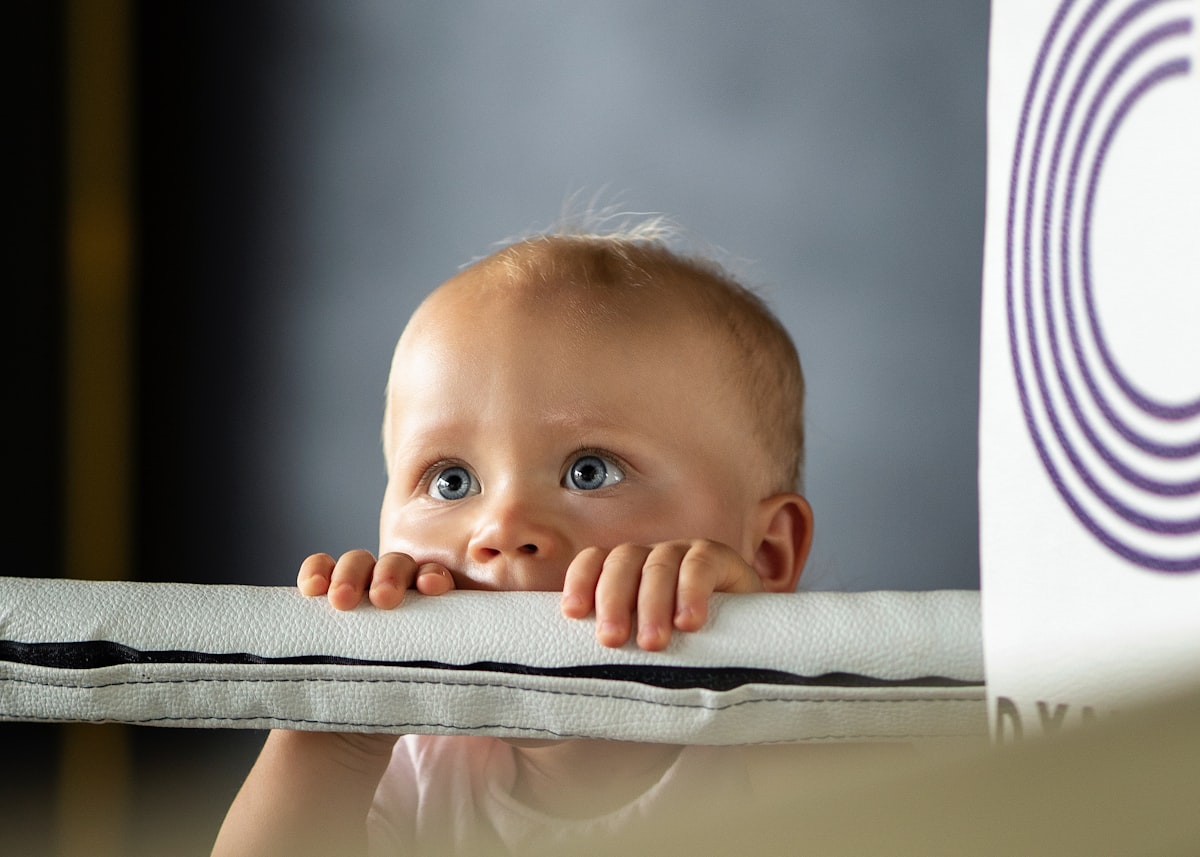 a baby with blue eyes related to Purple Reign: Creating a Majestic Nursery with Purple Baby Bedding