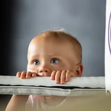 a baby with blue eyes related to Purple Reign: Creating a Majestic Nursery with Purple Baby Bedding