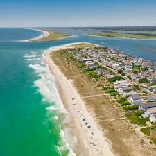 a beach with houses and water related to Wilmington's Cozy Charms: Find Your Perfect Bed and Breakfast