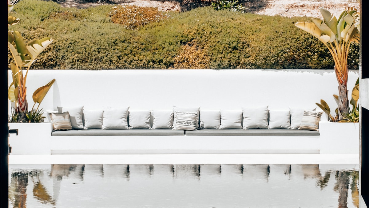 a beautiful garden, and a luxurious lounge sofa with a refined white design. The elegance complements the modern design house. The tranquil water feature reflects the beautiful surroundings, creating a serene and stylish atmosphere. related to Elevate Your Relaxation: The Ultimate Guide to Outdoor Lounge Beds
