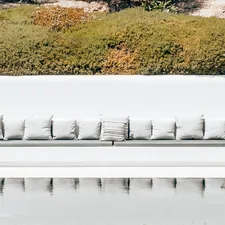 a beautiful garden, and a luxurious lounge sofa with a refined white design. The elegance complements the modern design house. The tranquil water feature reflects the beautiful surroundings, creating a serene and stylish atmosphere. related to Elevate Your Relaxation: The Ultimate Guide to Outdoor Lounge Beds