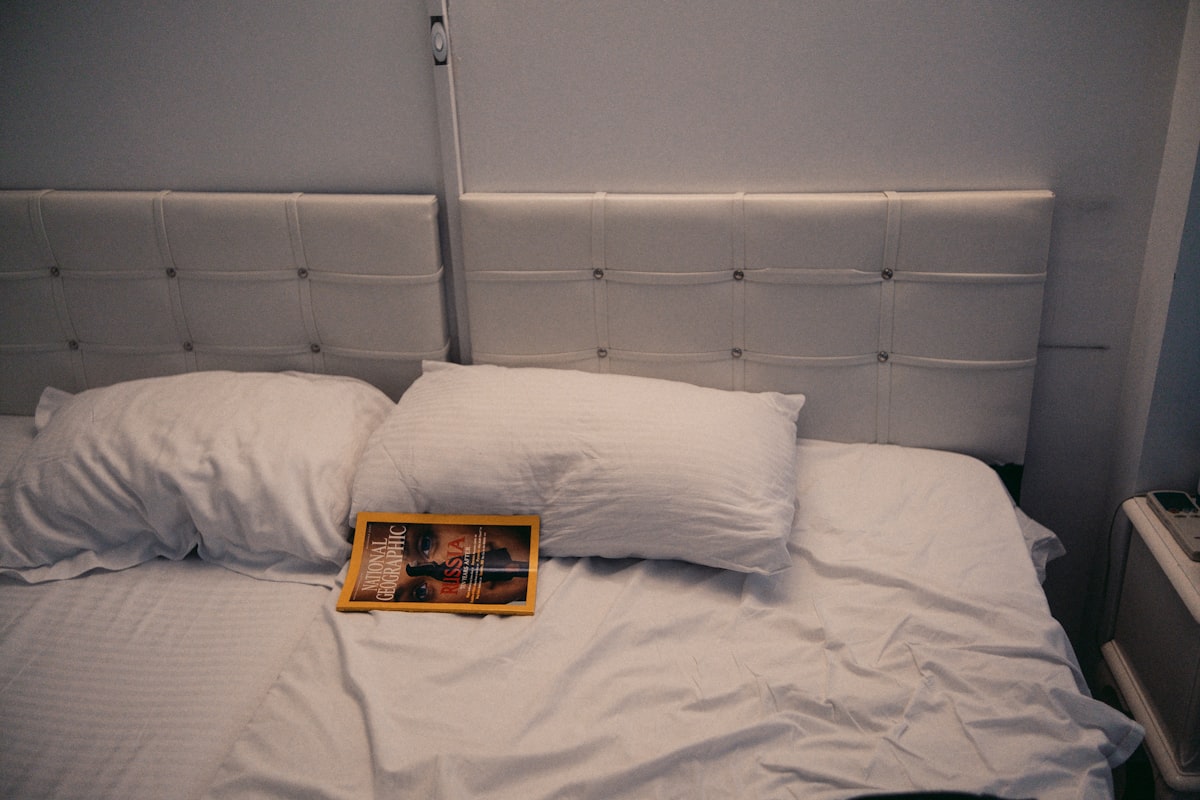 A bed is made with white pillows and sheets. related to The Elegance of White Leather Bed Design