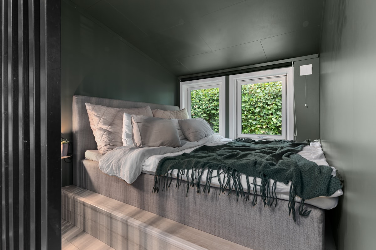 A bed sitting in a bedroom next to a window related to Cozying Up in a Small Space: Tiny House Bed Ideas