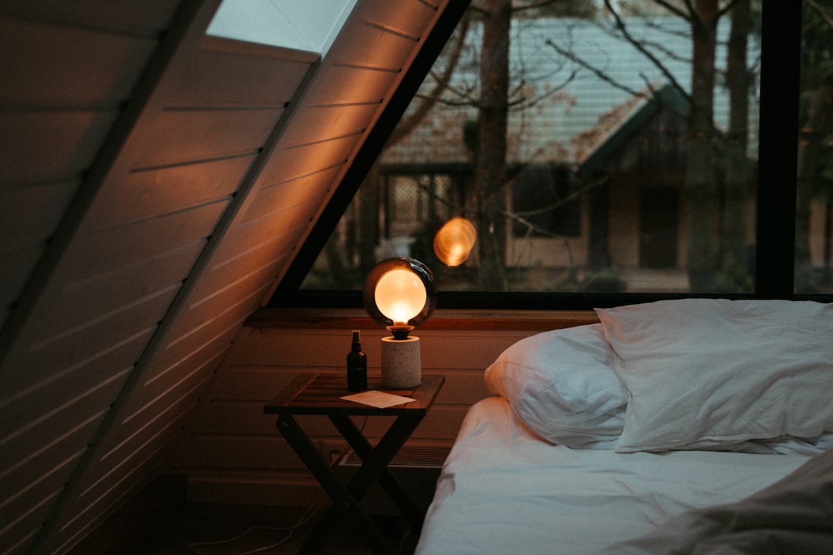a bed sitting under a window next to a night stand related to Cozy Nights Ahead: Elevating Home Decor with Quilts & Coverlets Bedding