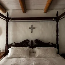 A bed with a cross on the wall above it related to Elegance Amidst Darkness: A Journey into Gothic Bed Frames