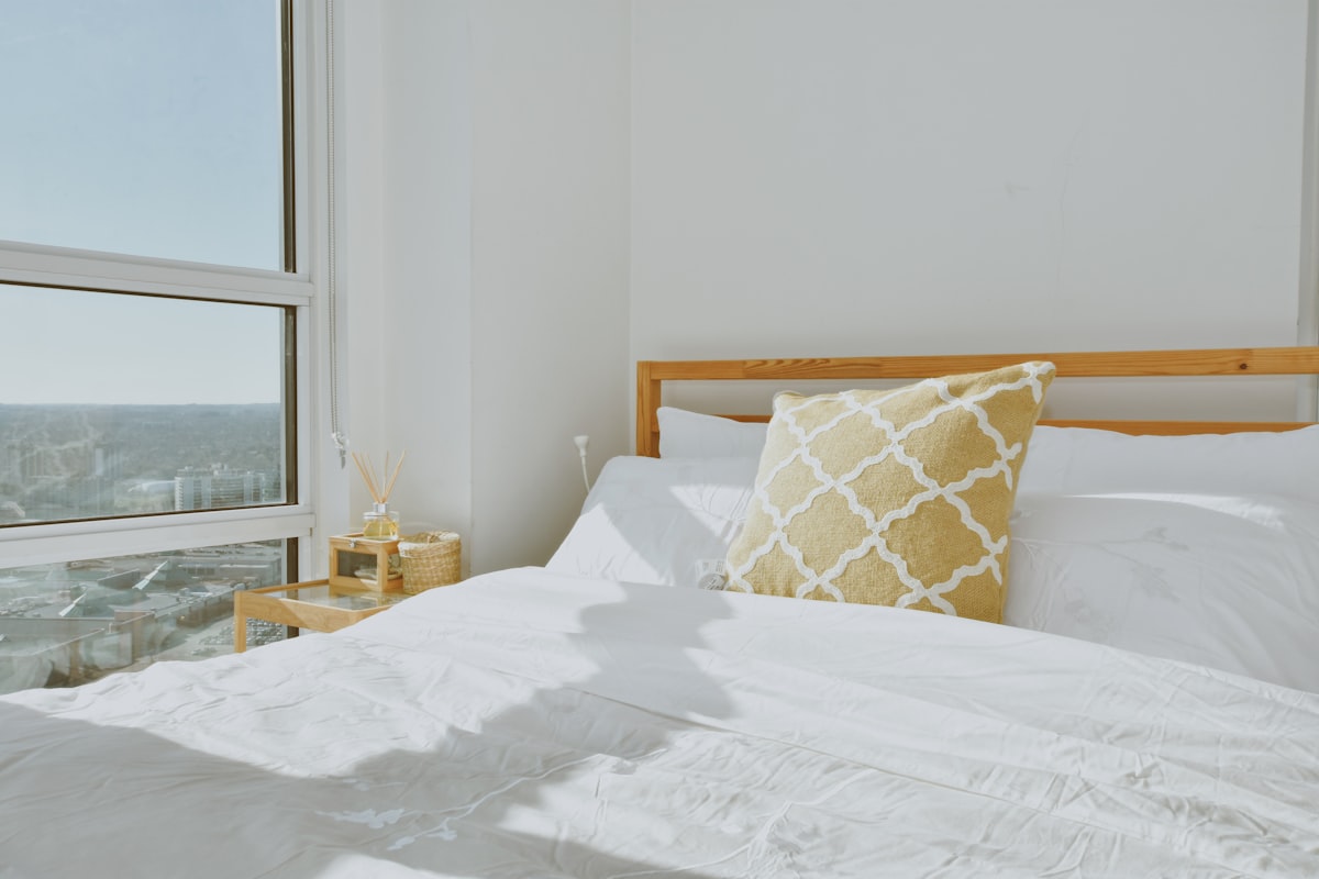 a bed with a white comforter and a yellow pillow related to Brighten Up Your Bedroom with a Yellow Coverlet for Your King-Sized Bed