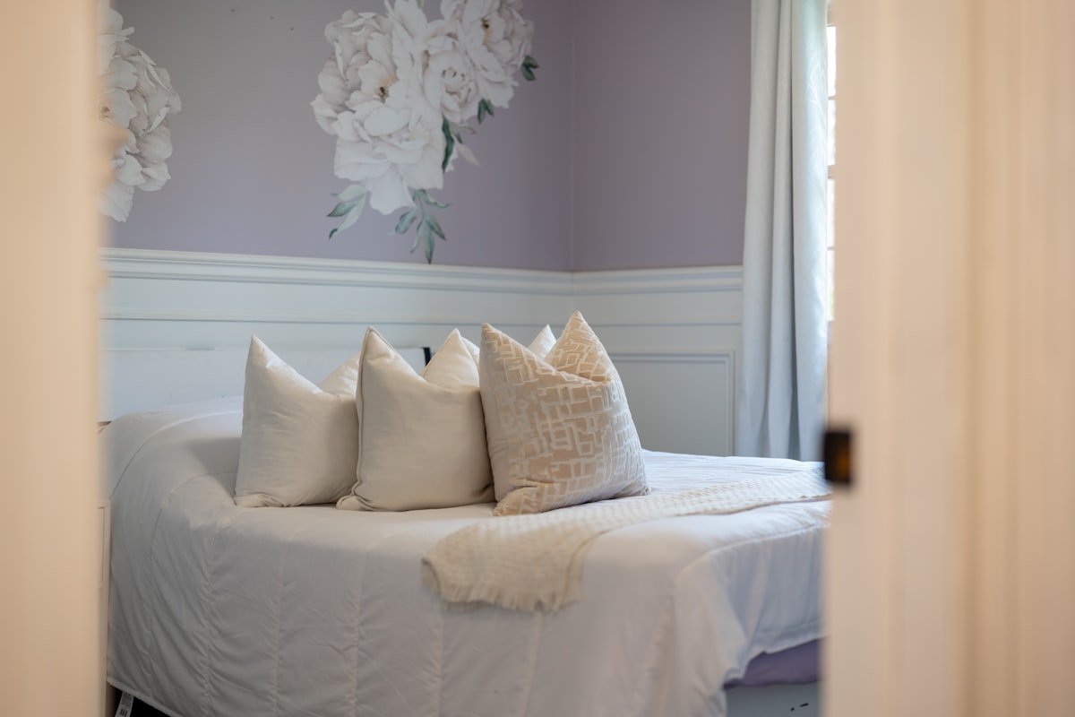 A bed with white pillows and floral wallpaper related to Simply Shabby Chic Bedding Hacks