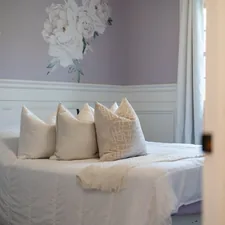 A bed with white pillows and floral wallpaper related to Simply Shabby Chic Bedding Hacks