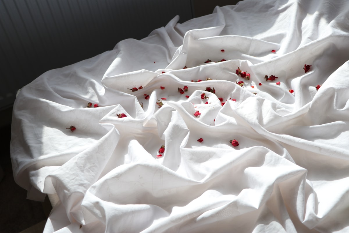 A bed with white sheets and red sprinkles on it related to Snuggle in Sweetness: Discover the Comfort of Pom-Pom Bedding