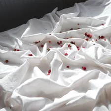 A bed with white sheets and red sprinkles on it related to Snuggle in Sweetness: Discover the Comfort of Pom-Pom Bedding
