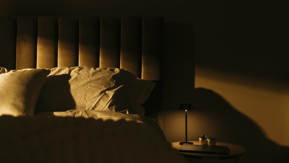 a bedroom with a bed and a night stand related to Exploring the Benefits of Light Headed Beds for Better Sleep