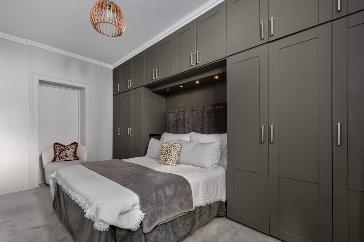 A bedroom with a bed, cabinets, and a chandelier related to Maximizing Space with a Twin Murphy Bed: A Game-Changing Solution