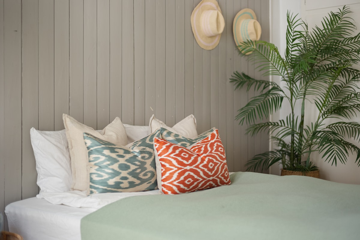 A bedroom with a bed, pillows and a potted plant related to Mint to Be: Refreshing Your Bedroom with Mint and Gray Bedding