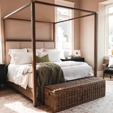a bedroom with a four poster bed and a wicker trunk related to The Ultimate Guide to Canopy Bed Frames