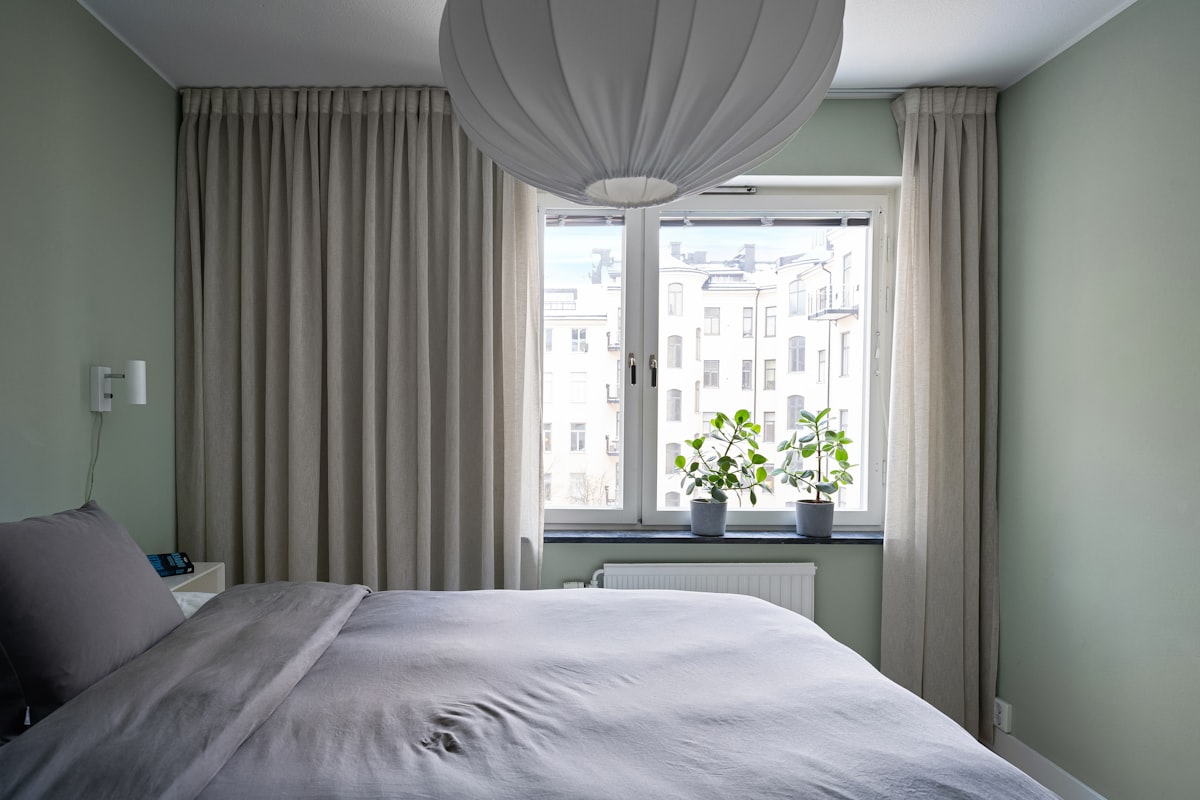 A bedroom with a large bed and a window related to Curtains or Valances: A Guide to Choosing the Perfect Window Treatment