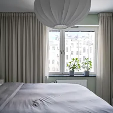 A bedroom with a large bed and a window related to Curtains or Valances: A Guide to Choosing the Perfect Window Treatment