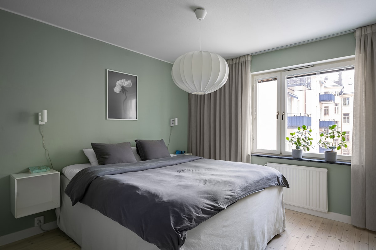 A bedroom with a large bed and a window related to Mint to Be: Refreshing Your Bedroom with Mint and Gray Bedding