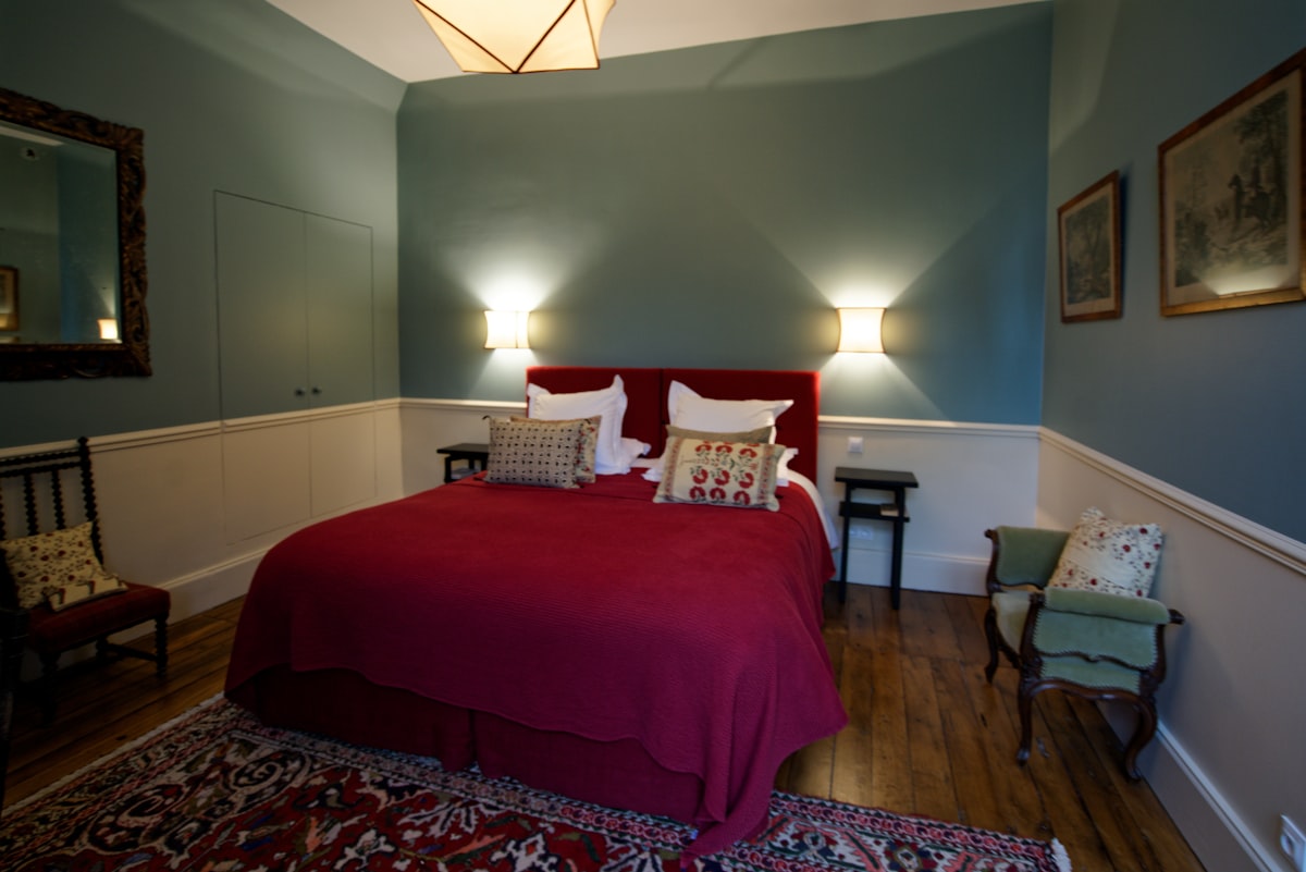 a bedroom with a red bed and a chair related to The Charm of St. Francisville: Discovering the Best Bed and Breakfasts