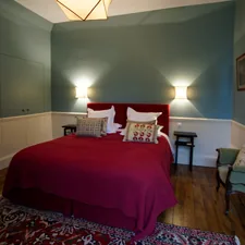 a bedroom with a red bed and a chair related to The Charm of St. Francisville: Discovering the Best Bed and Breakfasts