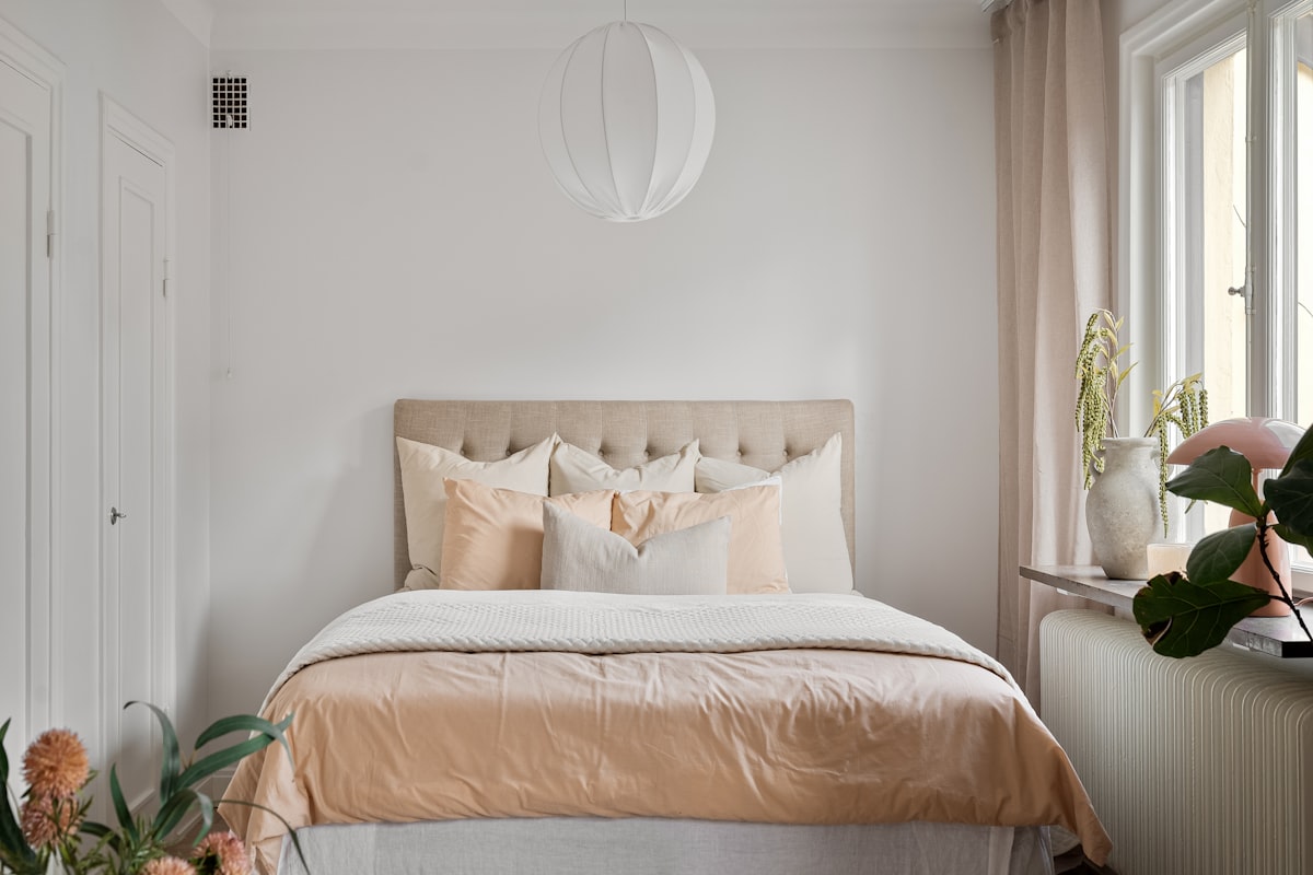 A bedroom with white walls and a bed with a beige headboard related to Valance Skirt for Bed: Elegant Bedding Solutions