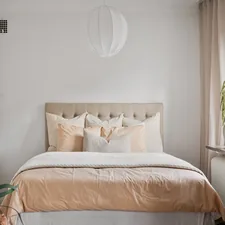 A bedroom with white walls and a bed with a beige headboard related to Valance Skirt for Bed: Elegant Bedding Solutions