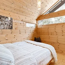A bedroom with wood walls and a bed related to Treehouse Loft Bed Wonderland