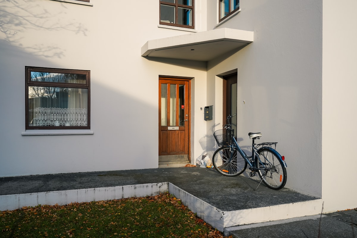 A bicycle parked outside a white house entrance. related to Elevate Your Home's First Impression: Front Door Entryway Ideas