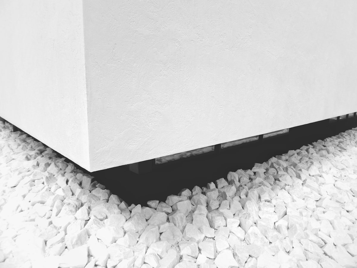 a black and white photo of rocks under a building related to Sleek and Smart: The Best Under Bed Shoe Storage Solutions