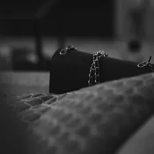 a black purse sitting on top of a bed related to The Dark Truth About Under Bed Restraints