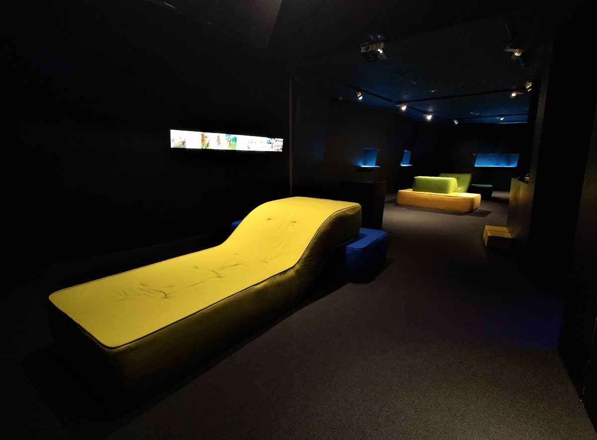 a black room with a yellow couch and a television related to Everything You Need to Know to Buy Tanning Bed