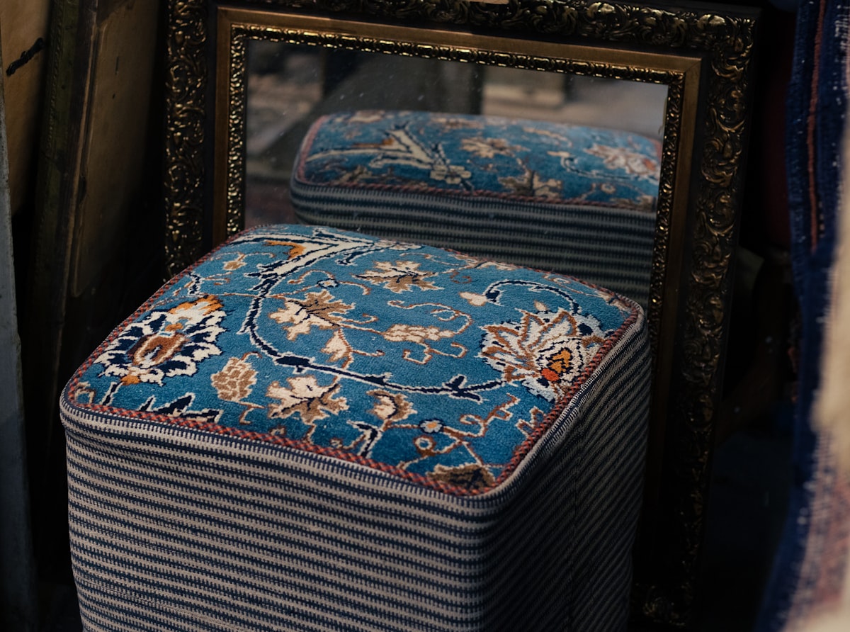 A blue ottoman sitting in front of a mirror related to Choosing the Perfect End of Bed Ottoman for Style and Functionality