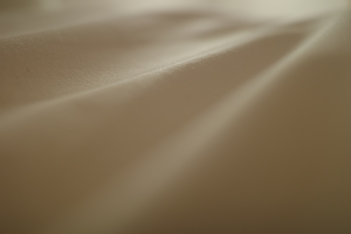 a blurry photo of a bed with white sheets related to Coverlets and Quilts: The Ultimate Guide