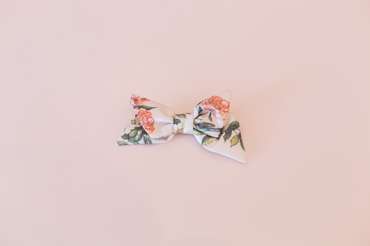 a bow tie with flowers on it on a pink background related to Sweet Dreams with Plum and Bow Bedding
