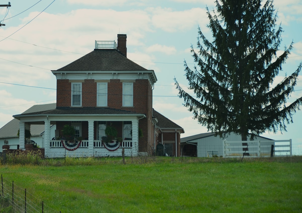 A brick farmhouse with a large evergreen tree. related to Charming Getaways in Pennsylvania Countryside