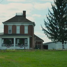 A brick farmhouse with a large evergreen tree. related to Charming Getaways in Pennsylvania Countryside