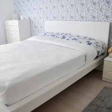 A bright and cozy modern bedroom interior featuring a white double bed, a matching nightstand with a teddy bear, and elegant blue and white floral wallpaper.📸 Photo by me IG: @margoevardson related to Elevate Your Bedroom with a Stylish White Platform Bed