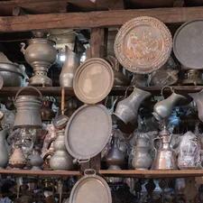 A bunch of pots and pans that are on a shelf related to Cast Iron Chiminea for Sale - One of a Kind Decorative Metal Art