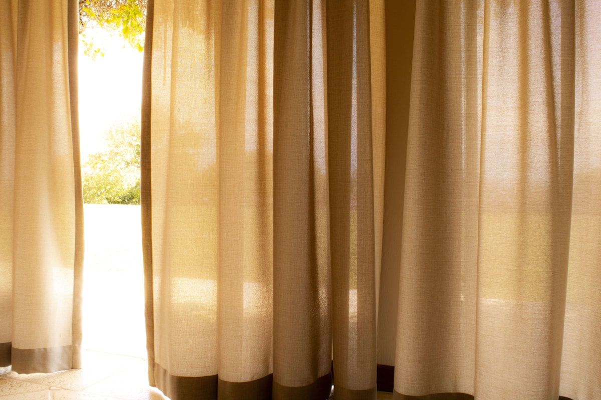 a cat sitting on the floor in front of a window related to Window Curtains & Valances