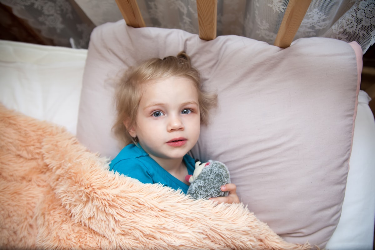 a child lying in a bed related to Dreamland Delights: The Ultimate Guide to Toddler Bedding for Girls