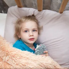 a child lying in a bed related to Dreamland Delights: The Ultimate Guide to Toddler Bedding for Girls