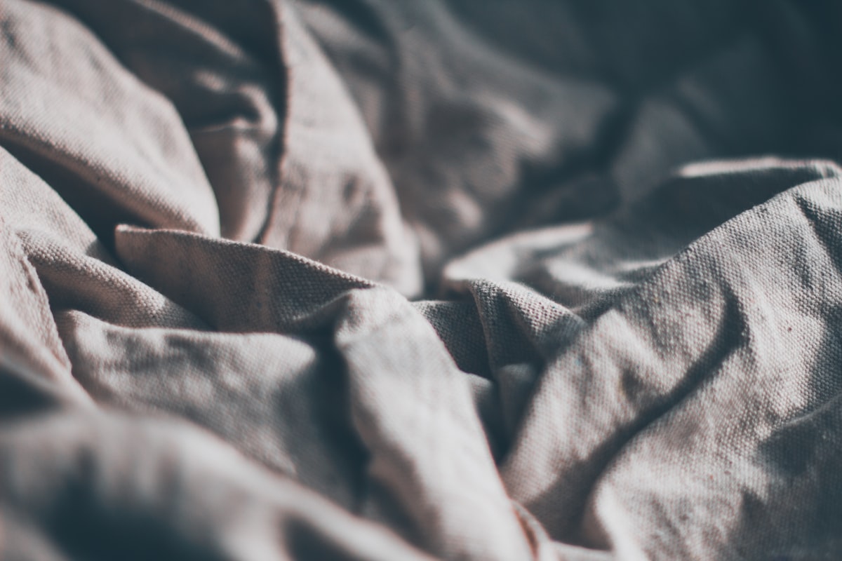 a close up of a bed with a white comforter related to Understanding the Difference Between Coverlet and Bedspread