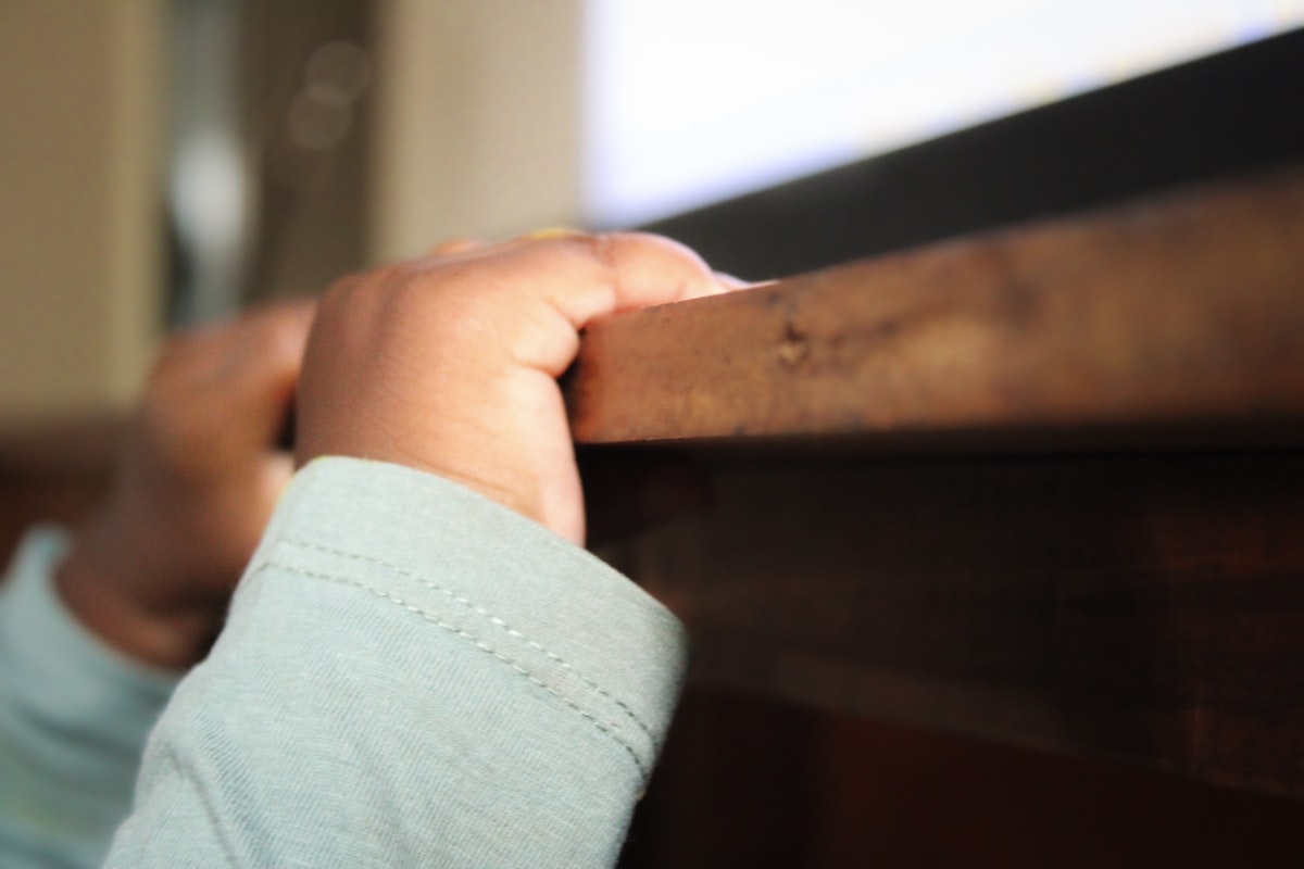 a close up of a child's hand on a rail related to Building Safety: A Guide to DIY Toddler Bed Rails