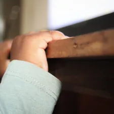 a close up of a child's hand on a rail related to Building Safety: A Guide to DIY Toddler Bed Rails