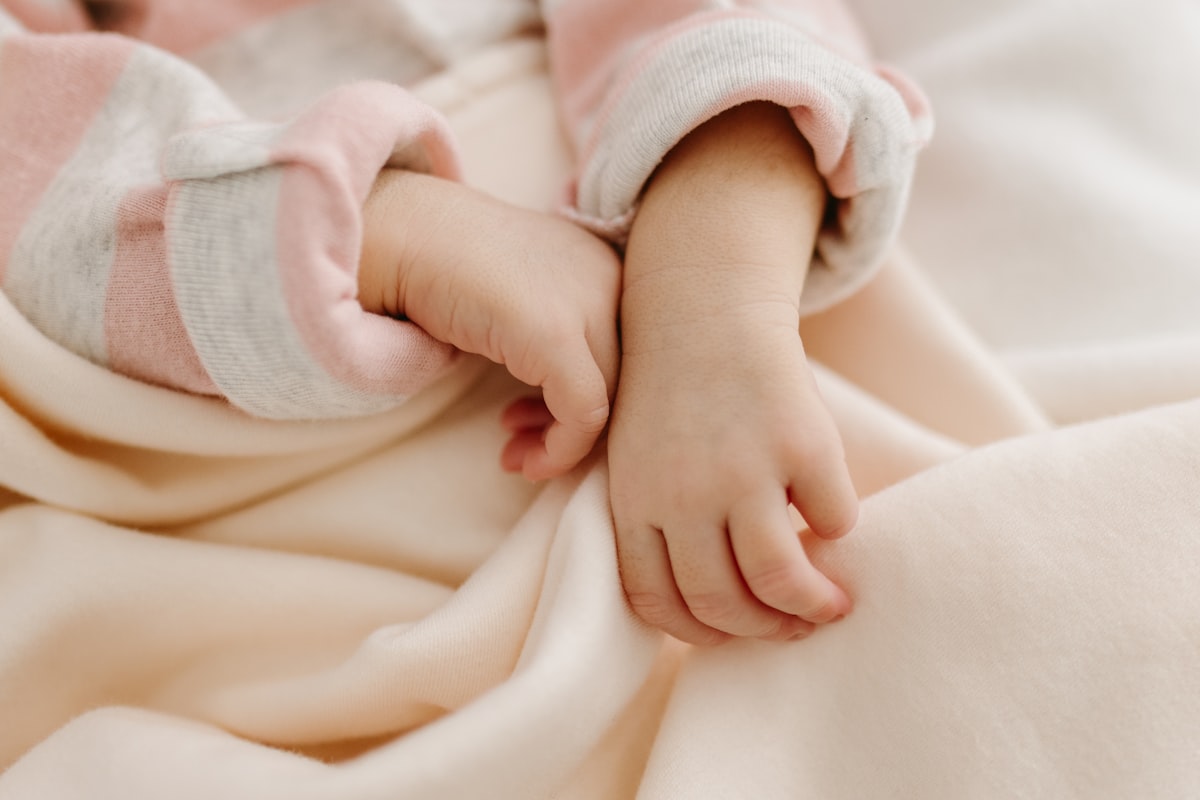 a close up of a person holding a baby's hand related to Creating a Cozy Nursery with Peach Baby Bedding