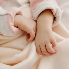 a close up of a person holding a baby's hand related to Creating a Cozy Nursery with Peach Baby Bedding