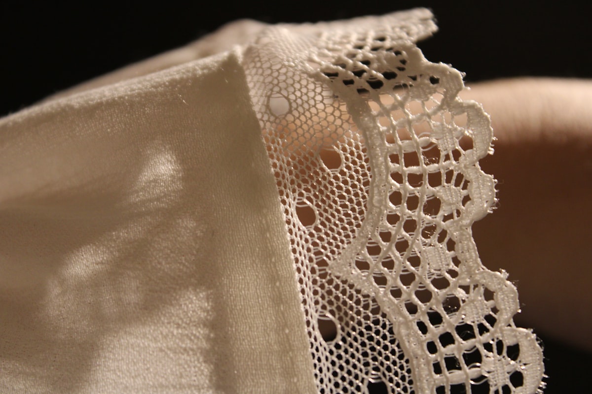 A close up of a person's hand holding a piece of lace related to Battenburg Lace Valances: A Comprehensive Guide