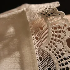 A close up of a person's hand holding a piece of lace related to Battenburg Lace Valances: A Comprehensive Guide